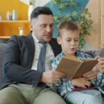 Vader en jongen lezen samen een boek op de bank