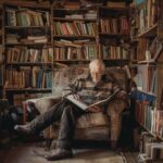Oudere man leest rustig een boek in een fauteuil tussen boekenkasten