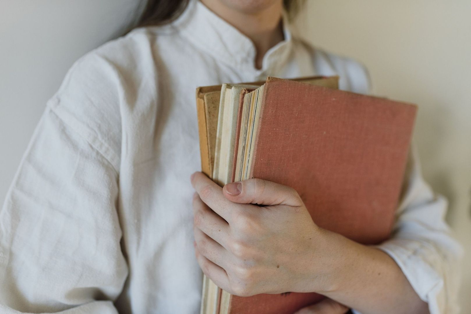 Persoon houdt een stapel oude boeken met versleten kaften vast