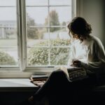 Lezer met open boek en kop koffie bij een zonnig raam